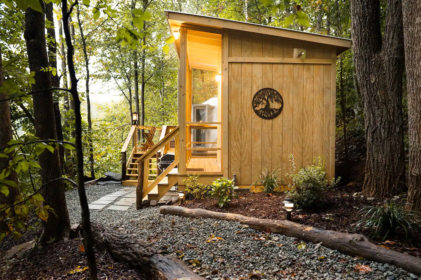 The path to the bath/kitchen is in the front, and the Tiny Geopod is in the distance, with an outdoor sitting space beyond.