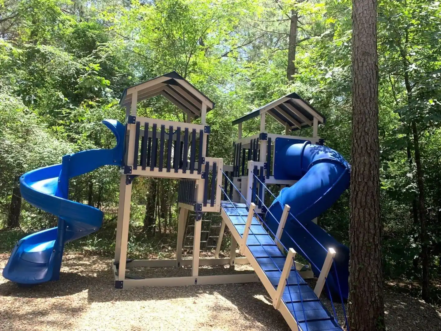 The large custom playset is nestled under the trees, providing excellent shade.