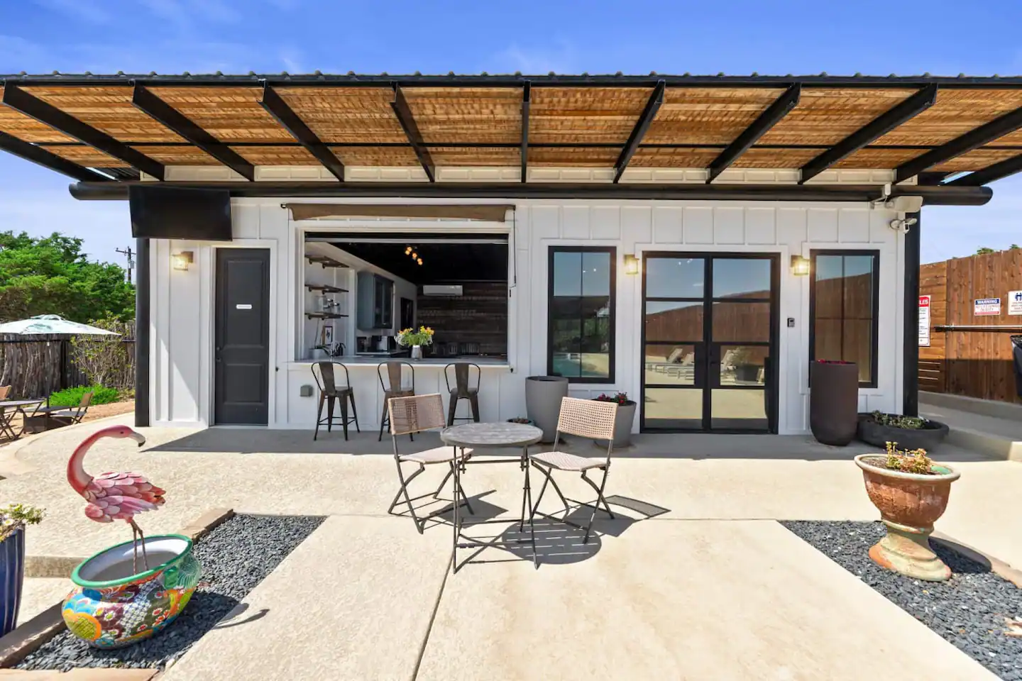 The Pool House features a bar area with a garage door opening.