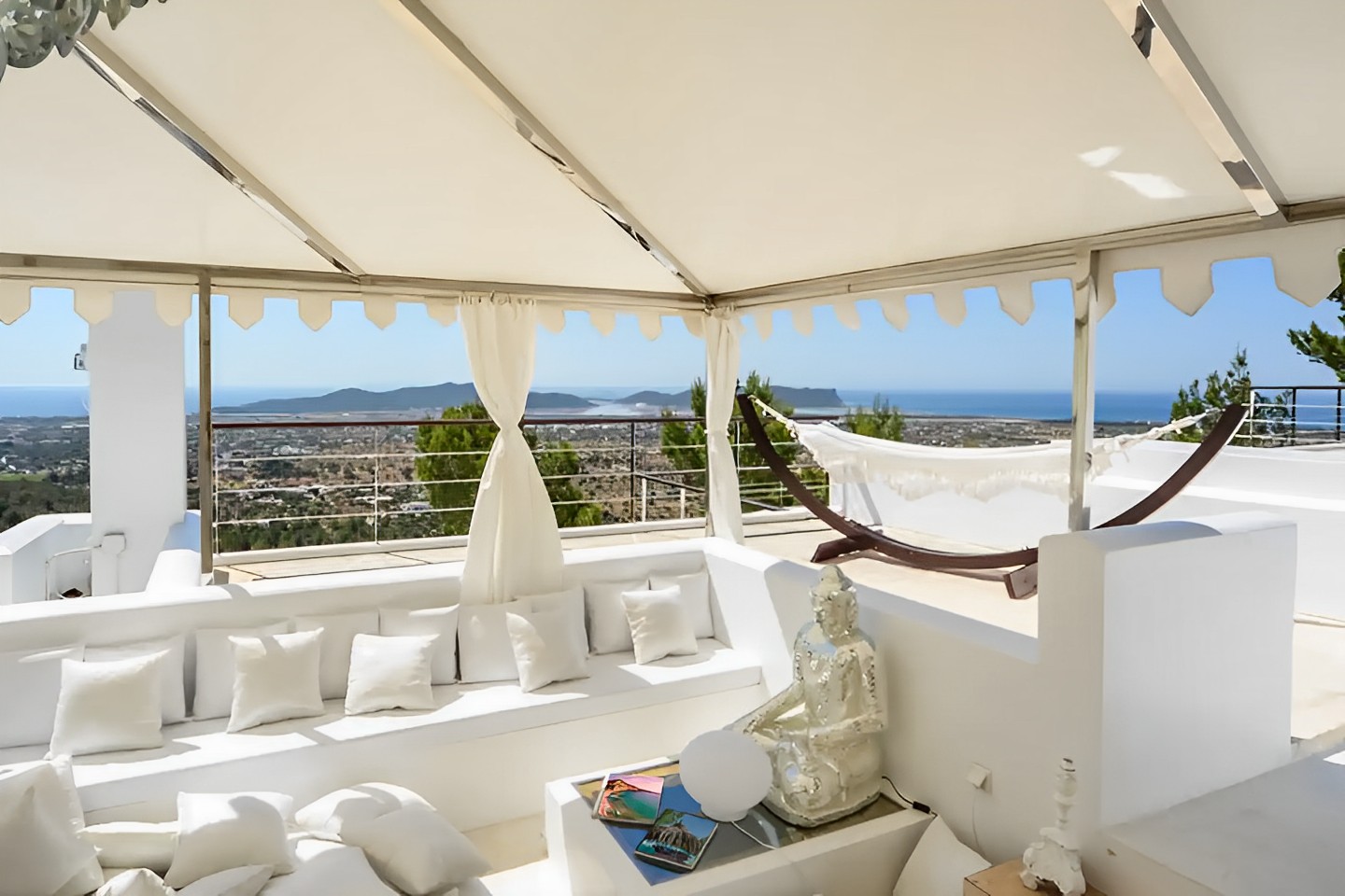A serene outdoor patio surrounded by lush greenery, featuring comfortable seating and a dining area,