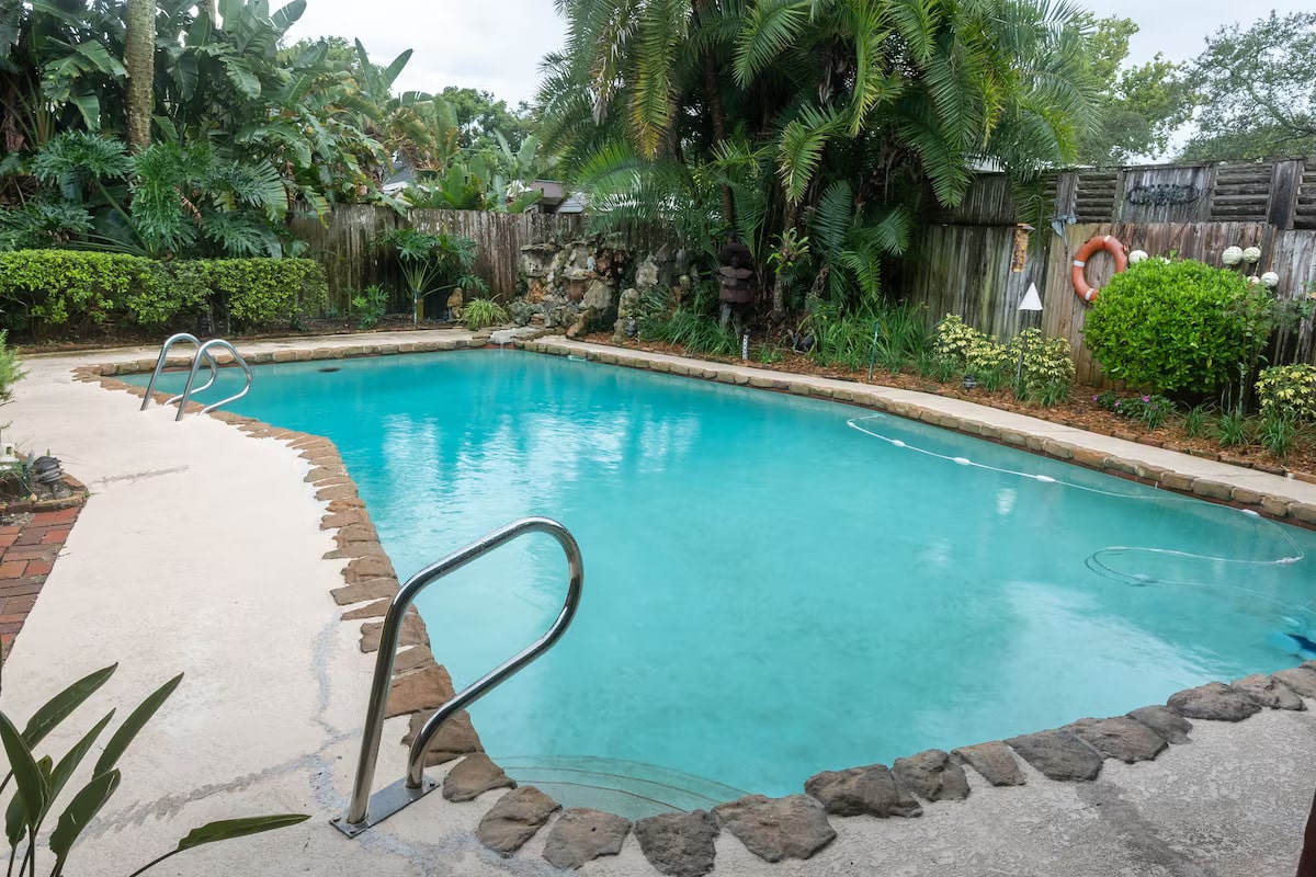 Lush pool area with tropical landscape and fountain.