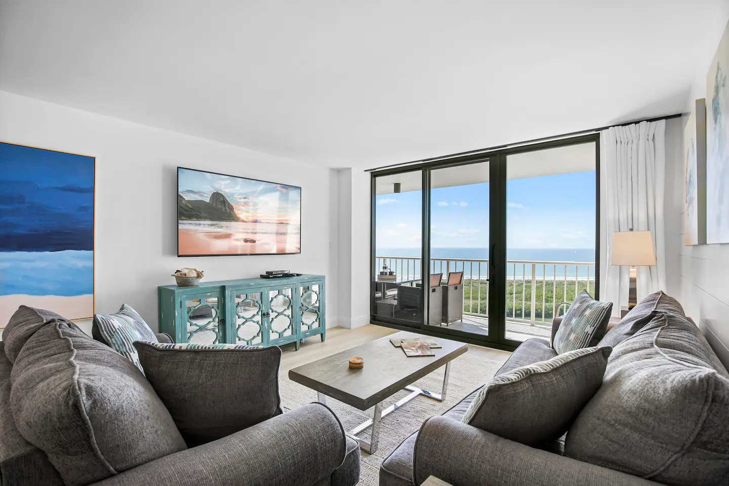 Comfy sofas in the coastal family room overlook Gulf of Mexico and pool
